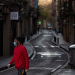 RAVAL DISTRICT, BARCELONA, SPAIN - 2020/04/05: A man wearing a face mask as a preventive measure against the COVID-19 coronavirus walks on an empty street. Due to the confinement order in Spain decreed by the Spanish President Pedro Sanchez to fight against the Coronavirus (Covid-19) the cities are practically empty. (Photo by Xavi Herrero/SOPA Images/LightRocket via Getty Images)