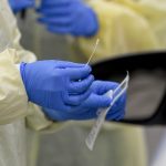 A detail photo of a nasal swab held by a Registered Nurse wearing gloves and a protective gown that she is about to use to do a test on a patient in their car at Penn State Health St. Joseph where they are conducting drive through coronavirus / COVID-19 testing and have taken extra precautions regarding entry to the hospital,  in Bern Township, PA Friday afternoon March 27, 2020.