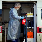 A medical worker wearing protective equipment sprays disinfectant at his ambulance after delivering a patient suspected of being infected with the coronavirus to the Pokrovskaya hospital in St.Petersburg, Russia, Monday, May 4, 2020. (AP Photo/Dmitri Lovetsky)