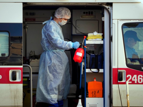 A medical worker wearing protective equipment sprays disinfectant at his ambulance after delivering a patient suspected of being infected with the coronavirus to the Pokrovskaya hospital in St.Petersburg, Russia, Monday, May 4, 2020. (AP Photo/Dmitri Lovetsky)