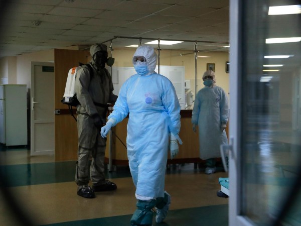 A serviceman of Belarus Ministry of Defence, left, and medical workers wearing protective gear seen at a local hospital in Minsk, Belarus, Tuesday, May 5, 2020. Despite the World Health Organization's call for Belarus to ban public events as coronavirus cases rise sharply, President Alexander Lukashenko says the country will go ahead with a parade to mark the 75th anniversary of the defeat of Nazi Germany. (AP Photo/Sergei Grits)