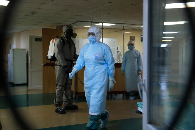 A serviceman of Belarus Ministry of Defence, left, and medical workers wearing protective gear seen at a local hospital in Minsk, Belarus, Tuesday, May 5, 2020. Despite the World Health Organization's call for Belarus to ban public events as coronavirus cases rise sharply, President Alexander Lukashenko says the country will go ahead with a parade to mark the 75th anniversary of the defeat of Nazi Germany. (AP Photo/Sergei Grits)