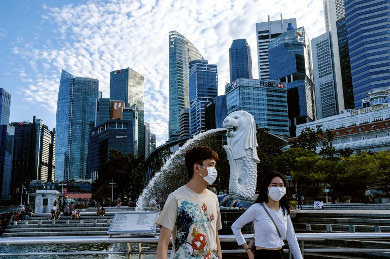 /// In this image taken Saturday, Mar. 14, 2020, a couple wearing face masks walk past the Merlion statue in Singapore. As the virus outbreak spreads ever further, it's becoming clear that some strategies are more likely to succeed in containing it: pro-active efforts to track down and isolate cases, access to basic, affordable public health and clear, reassuring messaging from leaders. (AP Photo/Ee Ming Toh)