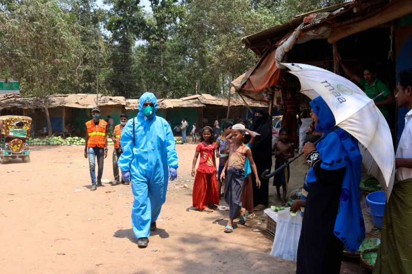 In this April 15, 2020, photograph, a health worker from an aid organization walks wearing a hazmat suit at the Kutupalong Rohingya refugee camp in Cox's Bazar, Bangladesh. There's been little if any coronavirus testing in Cox's Bazar, where more than a million members of Myanmar's Rohingya Muslim minority are packed into the world's largest refugee camp. (AP Photo/Shafiqur Rahman)