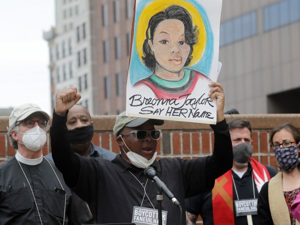 Kevin Peterson, founder and executive director of The New Democracy Coalition, center, displays a placard showing fallen Breonna Taylor as he addresses a rally, Tuesday, June 9, 2020, in Boston. Petersen advocates for changing the name of Faneuil Hall, as its namesake Peter Faneuil, was a slave owner. (AP Photo/Steven Senne)