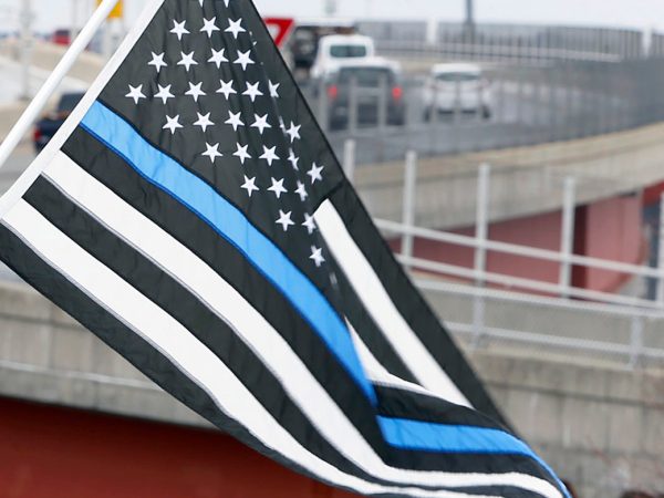 PORTLAND, ME - APRIL 8: Tim Seavey of Westbrook holds a Thin Blue Line flag next to grandson Ladainian Seavey on Tuesday at Harbor View Memorial Park as a motorcade accompanies fallen Maine State Police detective Ben Campbell’s casket across Casco Bay Bridge toward his funeral at Cross Insurance Arena. Seavey, who flies the flag year round at home, said he brough his grandson to the processional to teach him about respect for law enforcement. (Staff photo by Ben McCanna/Staff Photographer)