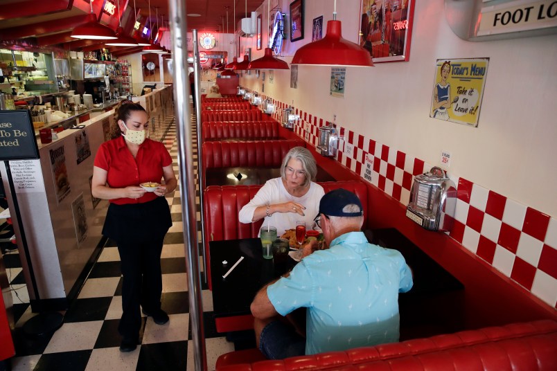 FILE - In this May 21, 2020, file photo, Lynn Tanner, center, and her husband Ryan, bottom right, are served lunch at Busy Bee Cafe in Ventura, Calif. Heading into Memorial Day weekend, California's mood was celebratory. The state had avoided dire predictions of a coronavirus surge, hospitalizations were declining, restaurants and most other businesses had reopened. As July 4th approaches, the mood has soured. Infection rates and hospitalizations are rising fast. Most bars have been ordered closed along with inside dining at restaurants. Many beaches are off-limits or have restrictions to limit crowds. Fireworks shows are canceled and Gov. Gavin Newsom is imploring Californians to avoid the holiday tradition of backyard barbecues and other gatherings of relatives and friends. (AP Photo/Marcio Jose Sanchez, File)