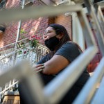 Natalia Afonso, 27, an international student from Brazil at Brooklyn College, sit on a stoop outside her home during an interview, Thursday July 9, 2020, in New York.  Afonso, who is studying teaching education and finished her first semester this spring, said she has lived in the U.S. for 7 years and “I don’t see myself moving back to Brazil at this point.  (AP Photo/Bebeto Matthews)