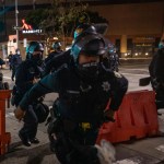 Police chase after protesters who refused to disperse at a protest on Saturday, July 25, 2020, in Oakland, Calif. The protest was organized in support of the city of Portland and against the presence of federal agents in US cities.(AP Photo/Christian Monterrosa)