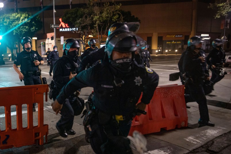 Police chase after protesters who refused to disperse at a protest on Saturday, July 25, 2020, in Oakland, Calif. The protest was organized in support of the city of Portland and against the presence of federal agents in US cities.(AP Photo/Christian Monterrosa)