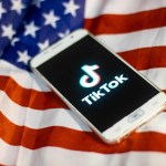 TikTok closeup logo displayed on a phone screen, smartphone on the American flag or U.S. flag, the national flag of the United States are seen in this multiple exposure illustration. Tik Tok is a Chinese video-sharing social networking service owned by a Beijing based internet technology company, ByteDance.  It is used to create short dance, lip-sync, comedy and talent videos. ByteDance launched TikTok app for iOS and Android in 2017 and earlier in September 2016 Douyin fror the market in China. TikTok became the most downloaded app in the US in October 2018. President of the USA Donald Trump is threatening and planning to ban the popular video sharing app TikTok from the US because of the security risk.  On August 3, 2020 in Thessaloniki, Greece.(Photo by Nicolas Economou/NurPhoto)