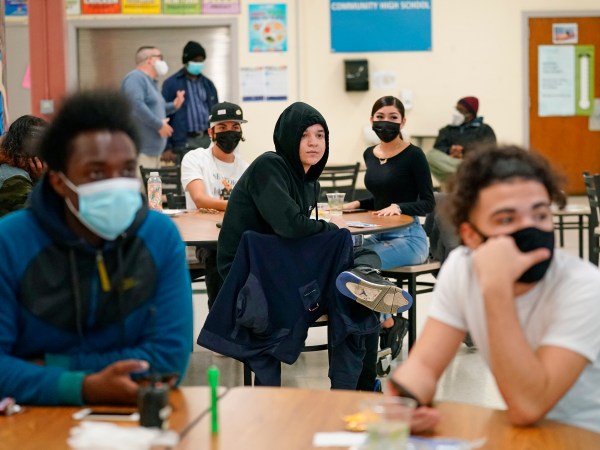 FILE- In this Oct. 29, 2020 file photo, students at West Brooklyn Community High School listen to questions posed by their principal during a current events-trivia quiz and pizza party in the school's cafeteria in New York. Students, parents and teachers continued anxiously watching New York City's coronavirus test results as the latest figures on Saturday, Nov. 14, 2020 fell under the city's threshold for shutting down school buildings, but Mayor Bill de Blasio warned that the city was at a “crucial” point in fighting the virus' resurgence. (AP Photo/Kathy Willen, File)