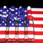 UKRAINE - 2020/11/13: In this photo illustration a syringe and ampules with fake COVID-19 vaccine seen with the U.S flag in the background. (Photo Illustration by Pavlo Conchar/SOPA Images/LightRocket via Getty Images)