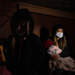 HOUSTON, TX - FEBRUARY 18: Surrounded by tarp and bedsheets, Evelyn Hernandez, 15, and her sister, Daeslyn Hernandez, 1, keep warm by the glow of a camping stove on their family’s front porch following an unprecedented winter storm in Houston, Texas on February 18, 2021. The Hernandez family lost power on Monday morning and are preparing for another deep freeze.  (Photo by Callaghan O’Hare for The Washington Post)