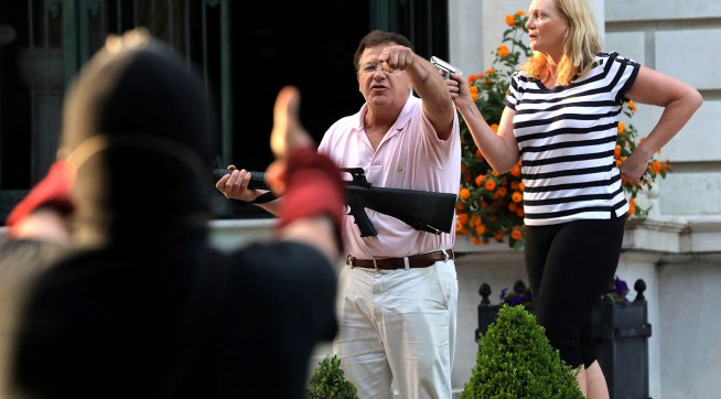 Armed homeowners Mark T. and Patricia N. McCloskey stand in front their house as they confront protesters marching to St. Louis Mayor Lyda Krewson's house on June 28, 2020. The protesters called for Krewson's resignation for releasing the names and addresses of residents who suggested defunding the police department. (Laurie Skrivan/St. Louis Post-Dispatch/TNS)