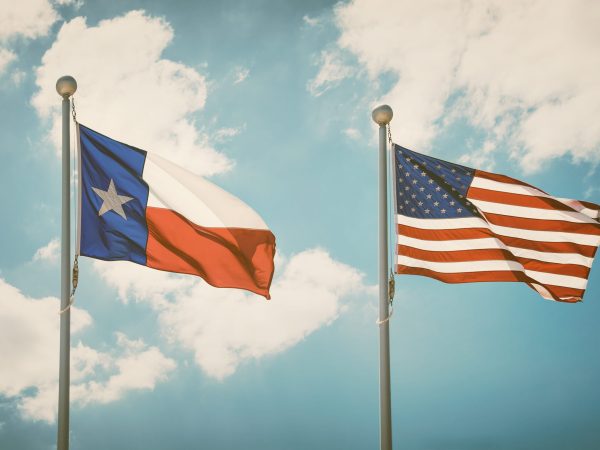 The state flag of Texas and American flag waving in the wind on flagpoles