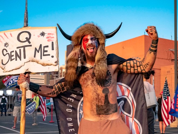 Jake A, 33, aka Yellowstone Wolf, from Phoenix, holds a QAnon sign, as he presents himself as a shamanist and consultant for the Trump supporters gathered in front of the Maricopa County Election Department where ballots are counted after the US presidential election in Phoenix, Arizona, on November 5, 2020. - President Donald Trump erupted on November 5 in a tirade of unsubstantiated claims that he has been cheated out of winning the US election as vote counting across battleground states showed Democrat Joe Biden steadily closing in on victory. (Photo by OLIVIER  TOURON / AFP) (Photo by OLIVIER  TOURON/AFP via Getty Images)